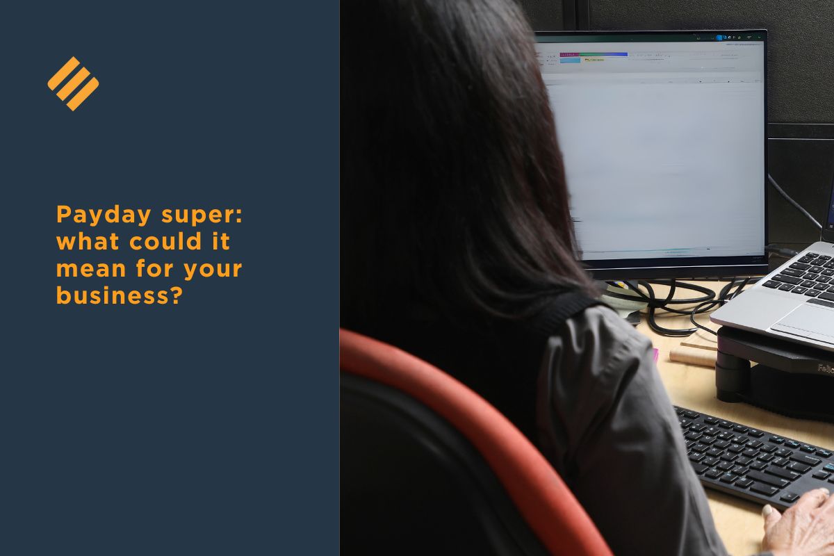 Person working at a desk with two computer screens, reviewing payroll or accounting data. The image includes a navy-blue overlay with orange text that reads, “Payday super: what could it mean for your business?”.