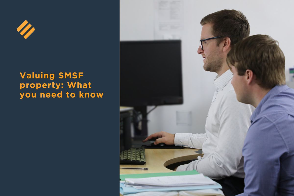 Two advisers sit at a desk reviewing information on a computer screen, discussing SMSF property valuation requirements. The image includes a dark blue panel with the heading Valuing SMSF property: What you need to know.