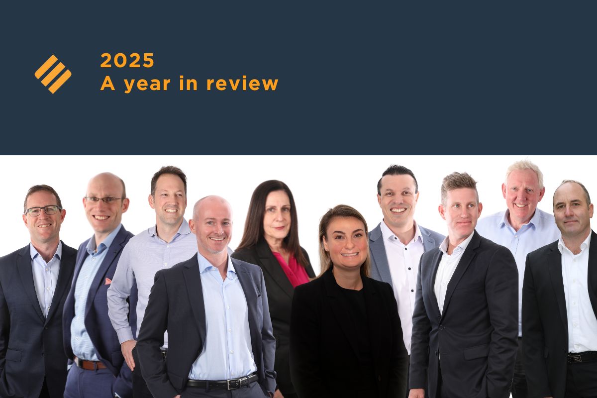 A group photo of the Johnsons MME leadership team standing together beneath a navy banner with the text “2025 A year in review” and the Johnsons MME brand icon.