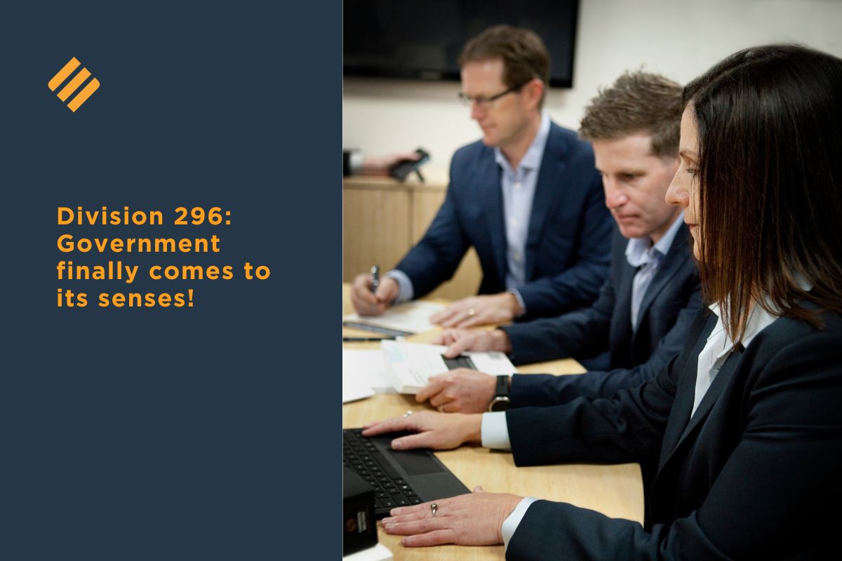 Three Johnsons MME team members in business attire reviewing documents and working on a laptop during a meeting about division 296 tax changes.