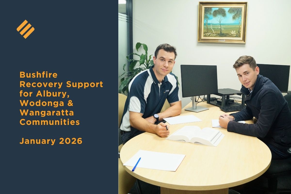Two Johnsons MME advisors meeting with a client at a table, reviewing documents as part of bushfire recovery support for Albury, Wodonga and Wangaratta communities.