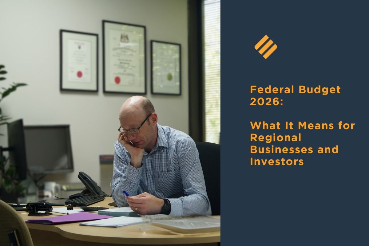 Johnsons MME accountant reviewing documents at a desk beside text about the 2026 Federal Budget and its impact on regional businesses and investors.